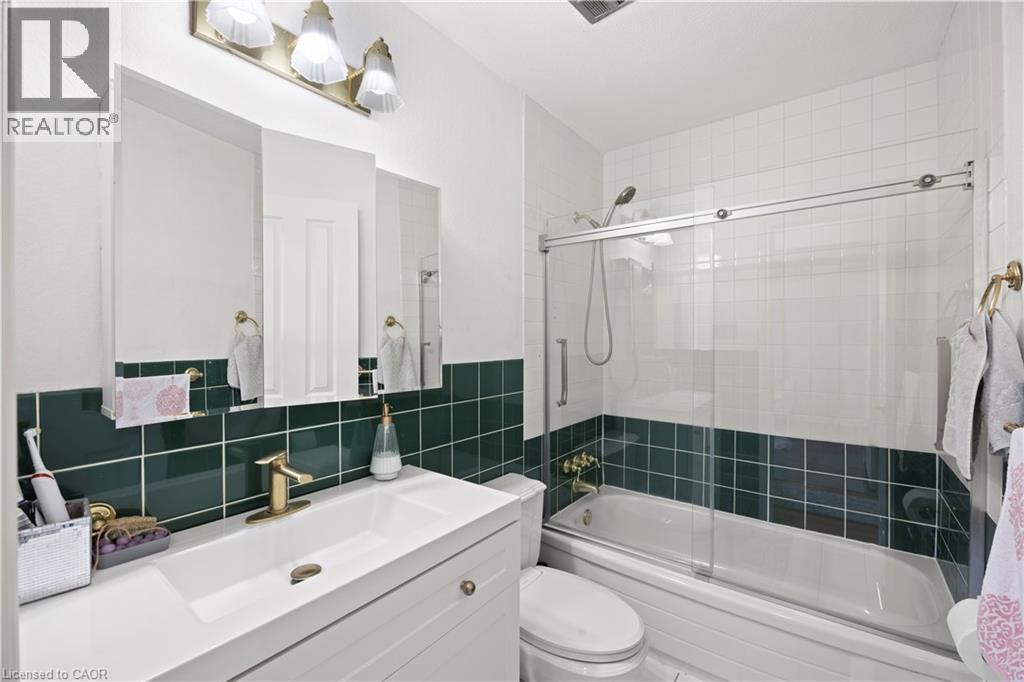 Bathroom featuring a white vanity with integrated sink, brass-finish faucet, and a three-door mirrored medicine cabinet - 277 Blackacres Boulevard, London, ON - Indoor Photo Showing Bathroom
