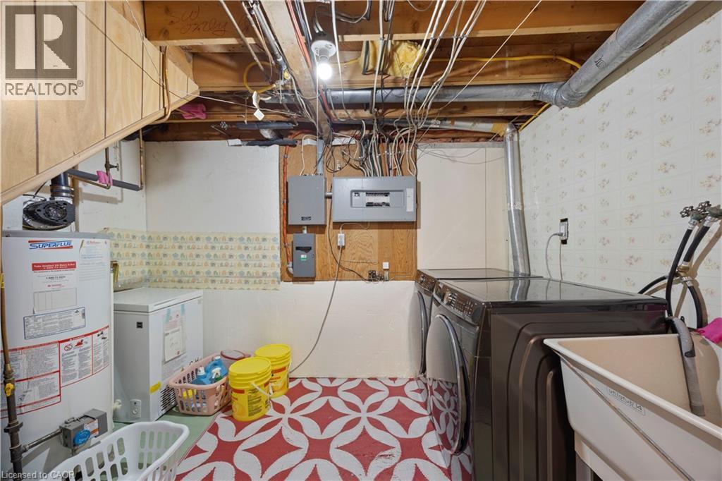 Laundry area featuring an exposed beam ceiling, patterned flooring, a utility sink, and electrical panels - 277 Blackacres Boulevard, London, ON - Indoor Photo Showing Laundry Room