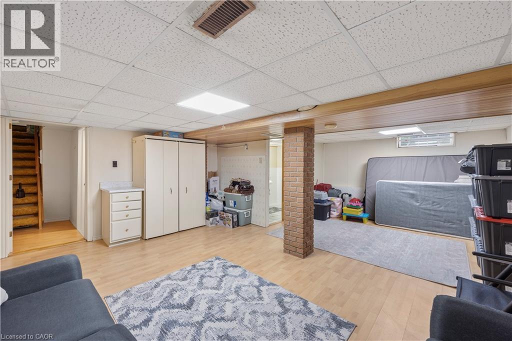 Finished basement featuring wood-finish flooring, drop ceiling with recessed lighting, and a brick-clad support column - 277 Blackacres Boulevard, London, ON - Indoor Photo Showing Basement