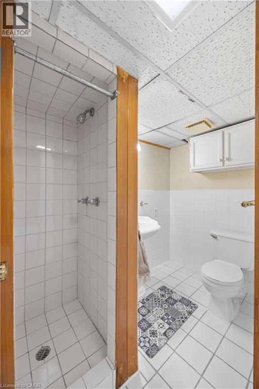 Bathroom featuring a white tile shower enclosure with chrome fixtures, a pedestal sink, and a toilet - 277 Blackacres Boulevard, London, ON - Indoor Photo Showing Bathroom