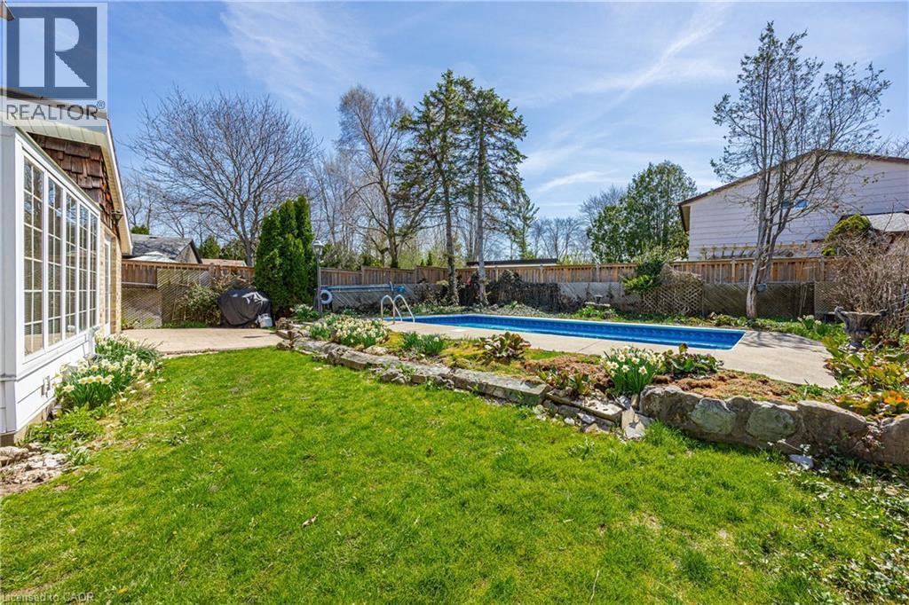 Private backyard oasis featuring an in-ground pool, surrounding concrete patio, and a stone-lined garden bed - 277 Blackacres Boulevard, London, ON - Outdoor With In Ground Pool With Backyard