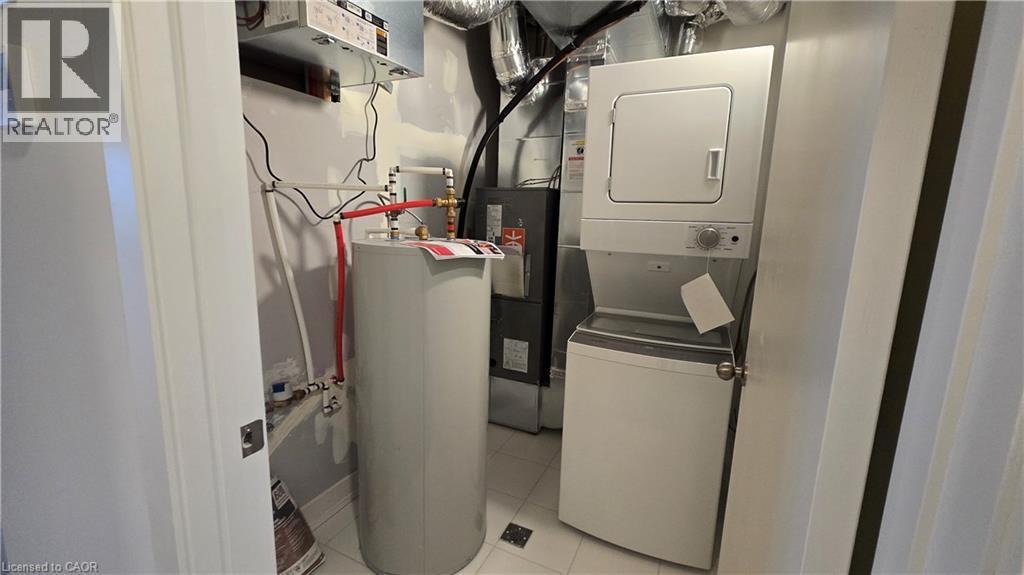 Dedicated utility space featuring a stacked washer and dryer, water heater, and HVAC system - 16 Melbourne Avenue Unit# 210B, St. Catharines, ON - Indoor Photo Showing Laundry Room