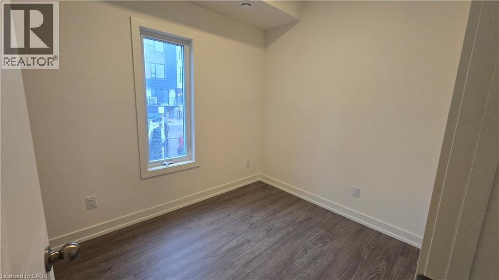 Room featuring wood-finish flooring, white baseboards, and a single window with white trim - 16 Melbourne Avenue Unit# 210B, St. Catharines, ON - Indoor Photo Showing Other Room
