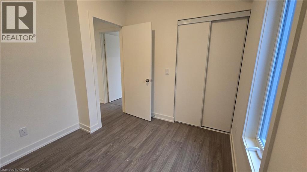 Interior room featuring wood-finish flooring, light-toned walls, and a white interior door - 16 Melbourne Avenue Unit# 210B, St. Catharines, ON - Indoor Photo Showing Other Room