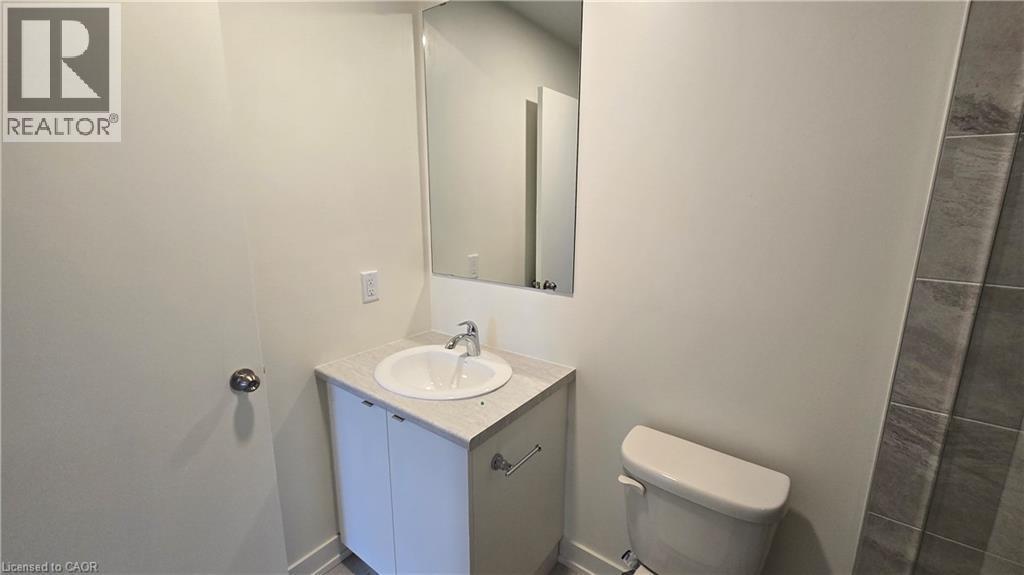 Bathroom featuring a white vanity with an undermount sink, a chrome faucet, and a light-toned countertop - 16 Melbourne Avenue Unit# 210B, St. Catharines, ON - Indoor Photo Showing Bathroom