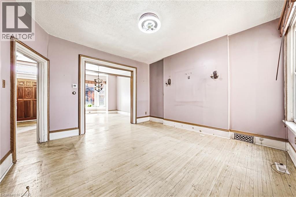 Spacious room featuring wood-finish flooring, white baseboards, and a semi-flush mount ceiling fixture - 116 Catharine Street S, Hamilton, ON - Indoor Photo Showing Other Room