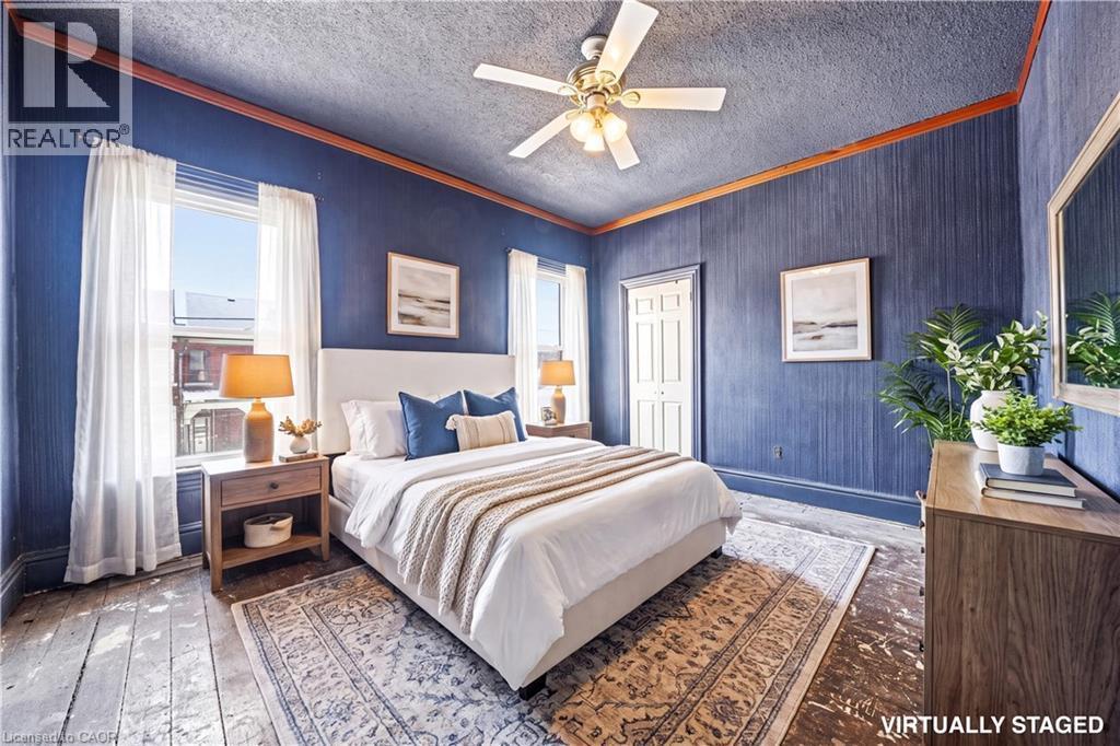 Bedroom featuring blue textured walls, wood-finish flooring, and white trim - 116 Catharine Street S, Hamilton, ON - Indoor Photo Showing Bedroom