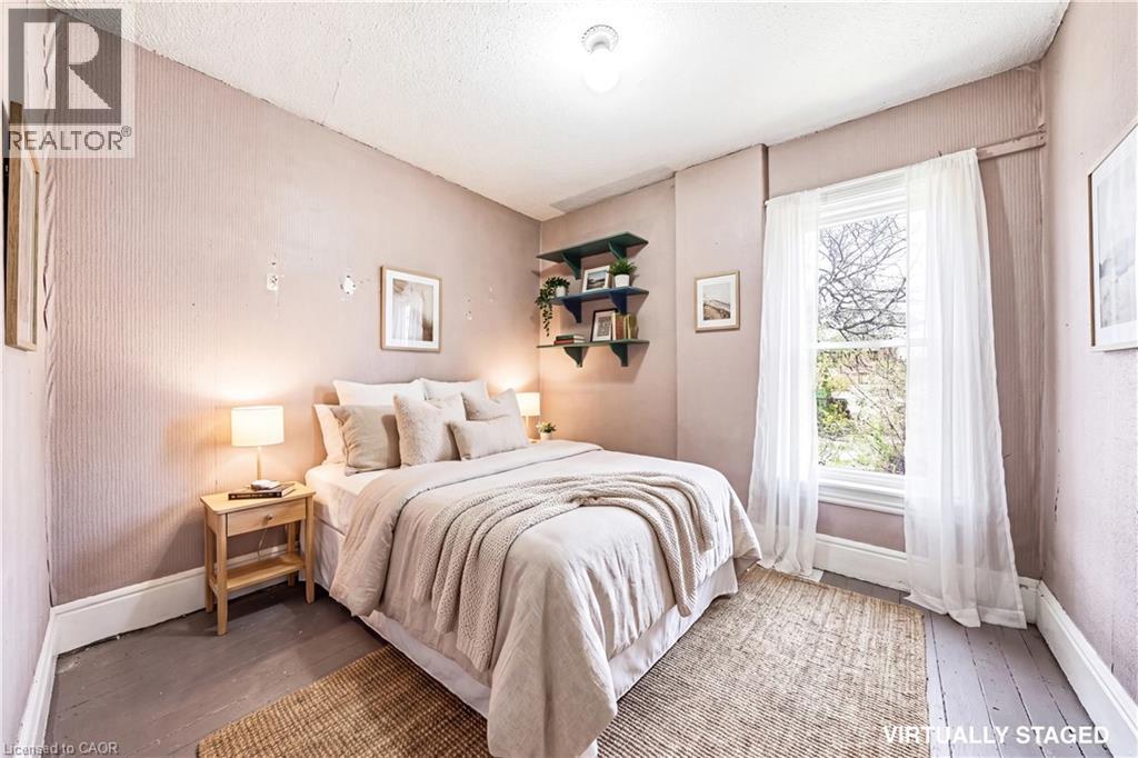 Spacious bedroom featuring a large window, hardwood flooring, and neutral wall tones - 116 Catharine Street S, Hamilton, ON - Indoor Photo Showing Bedroom