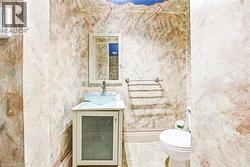 Featuring a white vanity with a glass-front cabinet, a clear vessel sink with a chrome faucet, a wall-mounted mirror, and tile flooring -