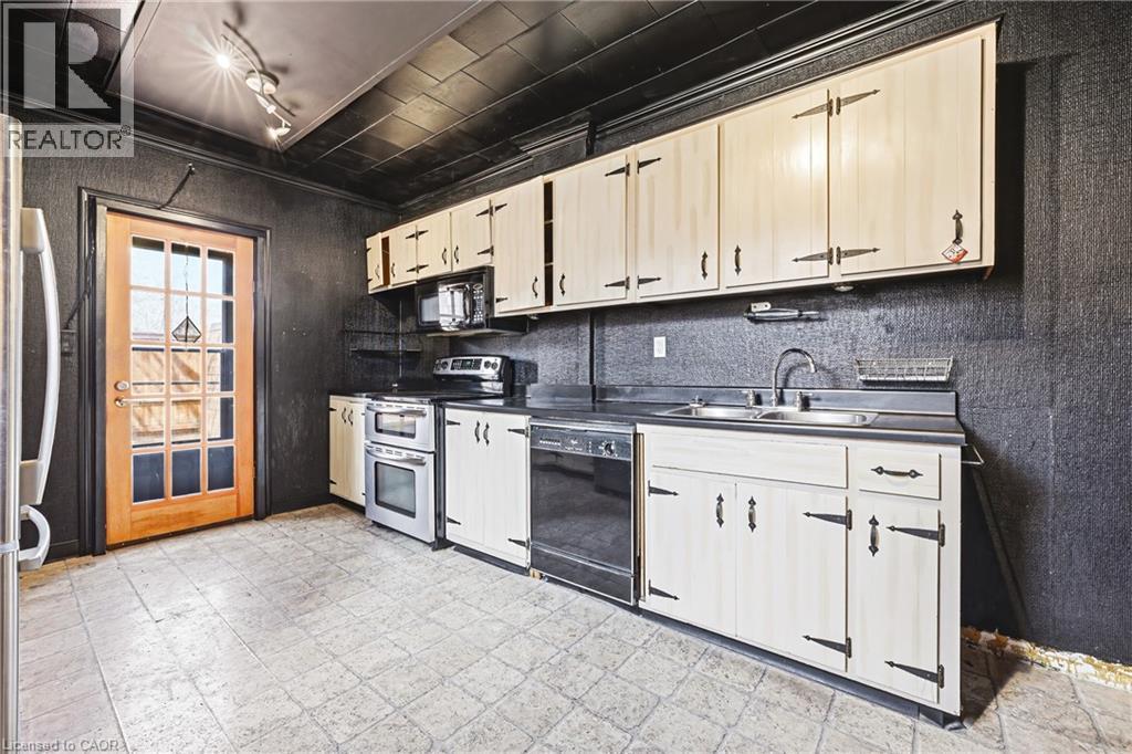 Kitchen featuring light-toned cabinetry with strap hinges, a stainless steel double oven, and a built-in dishwasher - 116 Catharine Street S, Hamilton, ON - Indoor Photo Showing Kitchen With Double Sink