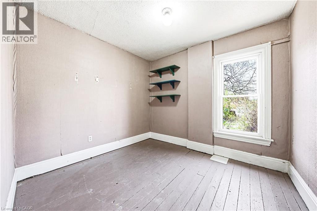 Room featuring a window with white trim, wood-finish flooring, and built-in shelving - 116 Catharine Street S, Hamilton, ON - Indoor Photo Showing Other Room