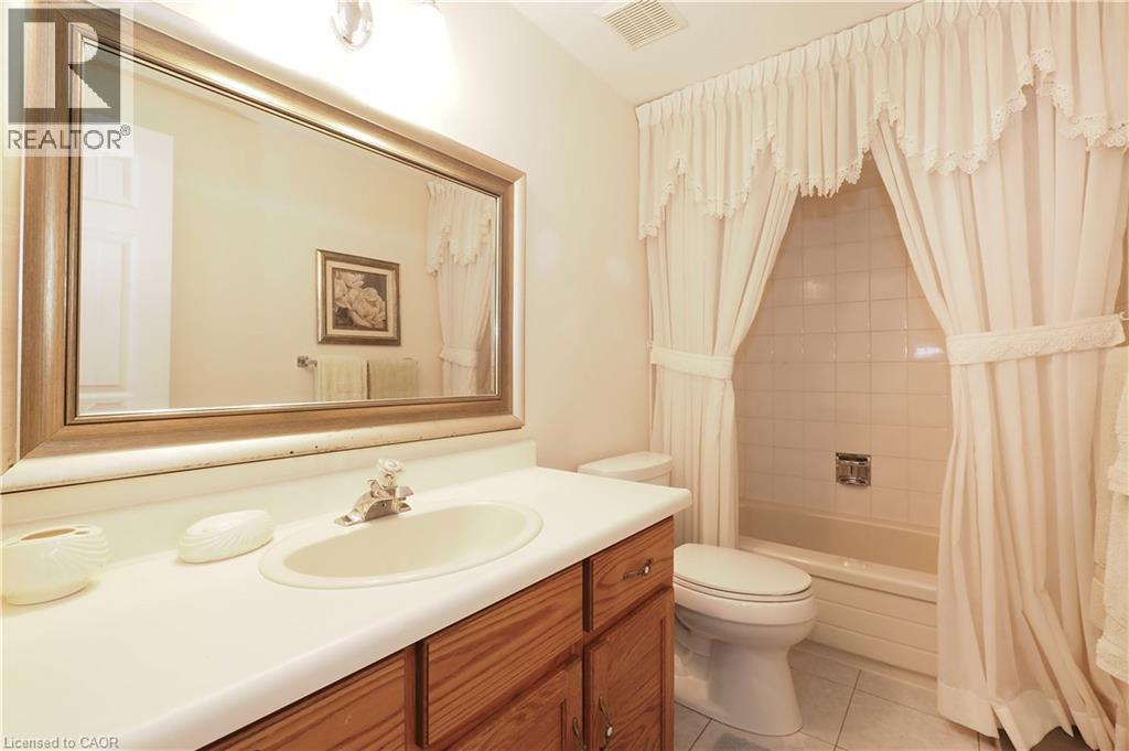 Full bathroom featuring vanity, shower / bath combo with shower curtain, and light tile patterned flooring - 89 Lynnhaven Court, Kitchener, ON - Indoor Photo Showing Bathroom