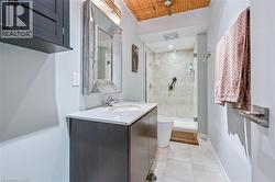 Bathroom featuring a stall shower, vanity, light tile patterned flooring, and wood ceiling -