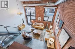 Living area featuring concrete floors, a high ceiling, brick wall, and a chandelier -