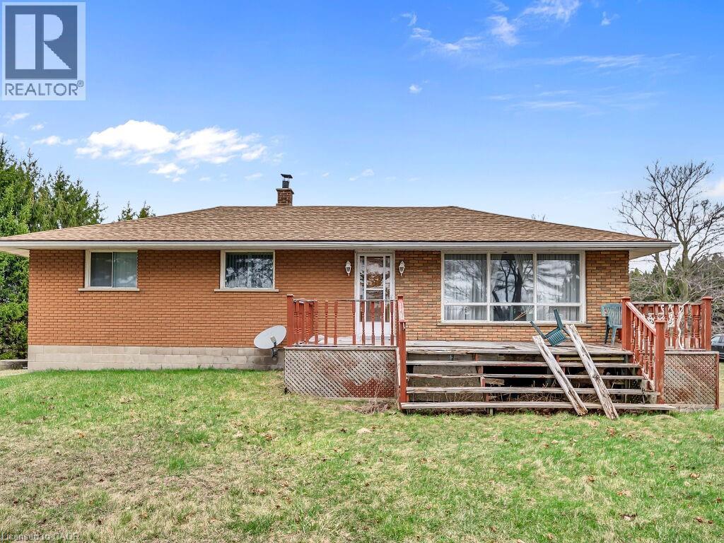 Brick exterior with multiple windows and a brown shingle roof - 1416 Highway 6, Hamilton, ON - Outdoor With Deck Patio Veranda