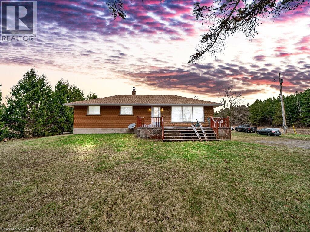 Brick exterior residence featuring a front deck with wooden railings, a pitched shingle roof, and multiple windows - 1416 Highway 6, Hamilton, ON - Outdoor With Deck Patio Veranda