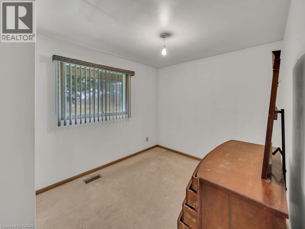 Bright room featuring a single window with vertical blinds, a ceiling-mounted light fixture, and neutral carpeting - 1416 Highway 6, Hamilton, ON - Indoor Photo Showing Other Room