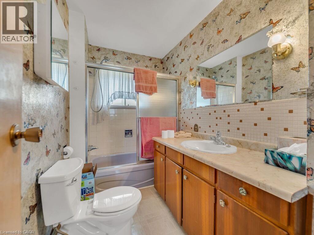 Bathroom featuring a single vanity with wood-finish cabinetry, a white drop-in sink, and a light-toned countertop - 1416 Highway 6, Hamilton, ON - Indoor Photo Showing Bathroom
