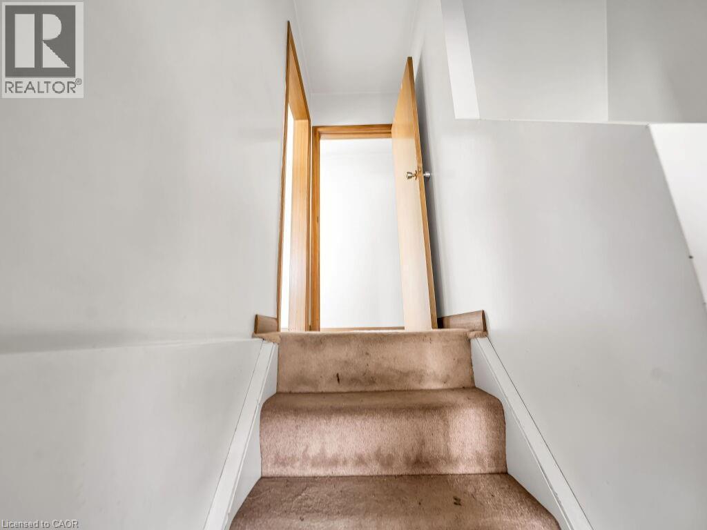 Carpeted staircase with white risers and light-colored walls leading to a doorway with a light wood-finish door and frame - 1416 Highway 6, Hamilton, ON - Indoor Photo Showing Other Room