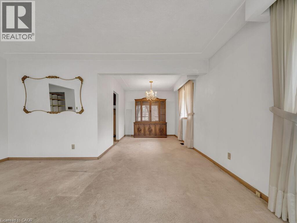 Open-concept living space featuring neutral-toned carpeting, white painted walls, and an ornate gold-framed mirror - 1416 Highway 6, Hamilton, ON - Indoor Photo Showing Other Room