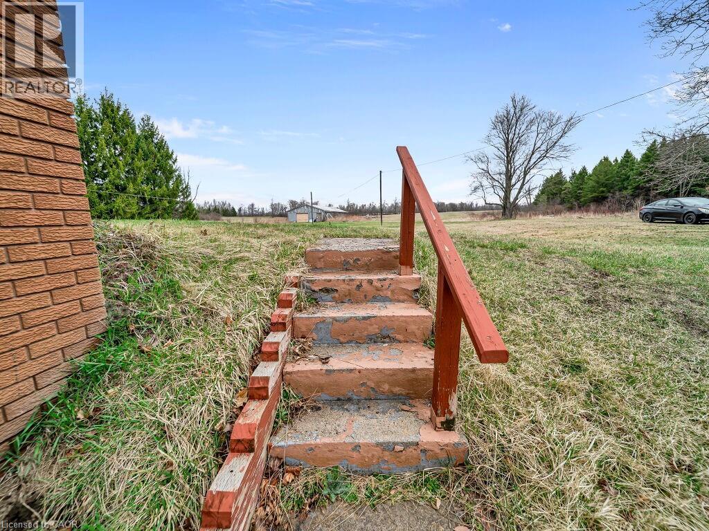Brick exterior featuring concrete steps with a red-painted handrail - 1416 Highway 6, Hamilton, ON - Outdoor
