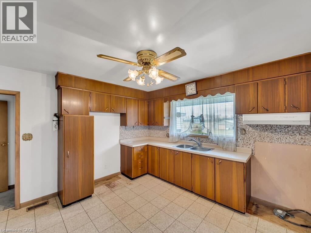 Kitchen featuring wood-finish cabinetry, tile flooring, and a double basin sink - 1416 Highway 6, Hamilton, ON - Indoor Photo Showing Kitchen With Double Sink
