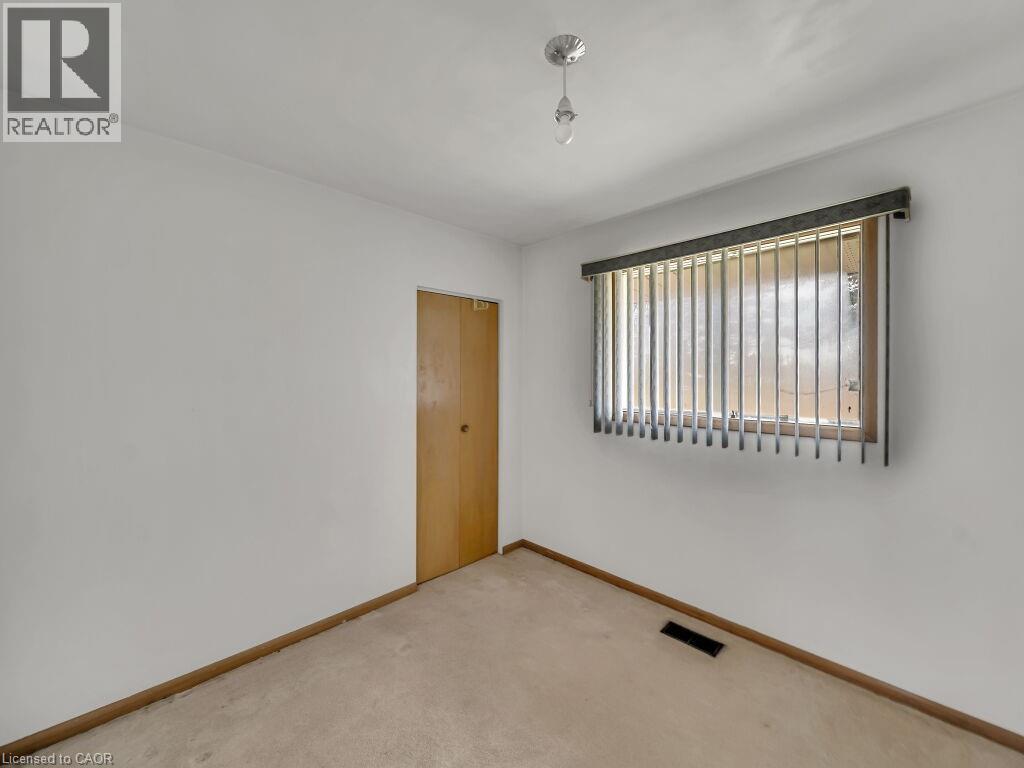 White-painted walls with light-toned carpeting and wood-finish baseboards - 1416 Highway 6, Hamilton, ON - Indoor Photo Showing Other Room