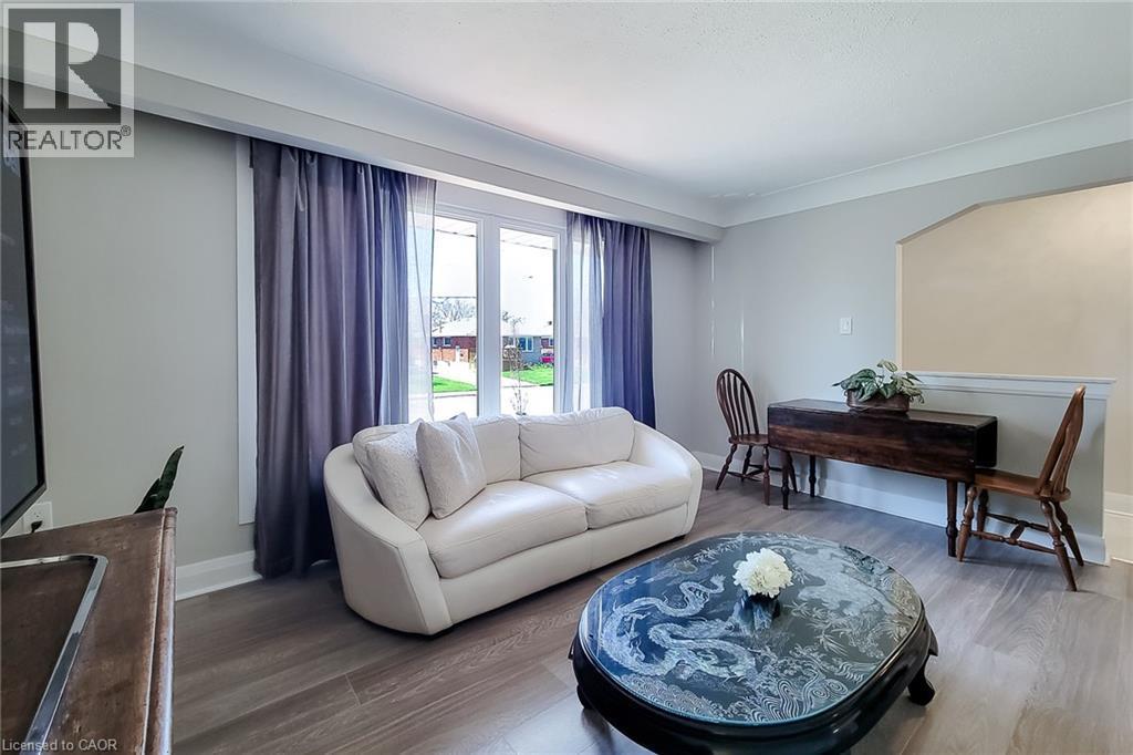Spacious living area featuring light-toned walls, crown molding, and wood-finish flooring - 103 East 45Th Street, Hamilton, ON - Indoor Photo Showing Living Room