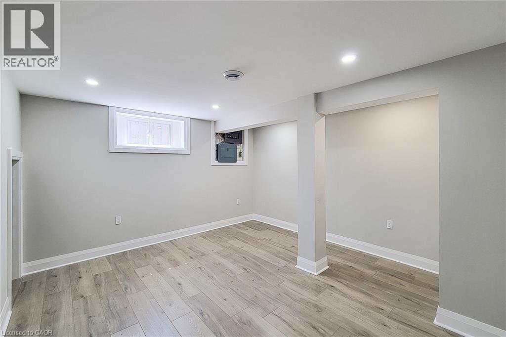 Finished lower-level room featuring wood-finish flooring, recessed lighting, a white framed window, and light-toned walls - 103 East 45Th Street, Hamilton, ON - Indoor