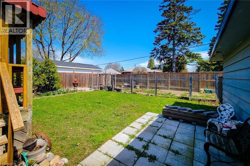 Expansive backyard featuring a green lawn, concrete patio, and perimeter wood fencing - 103 East 45Th Street, Hamilton, ON - Outdoor