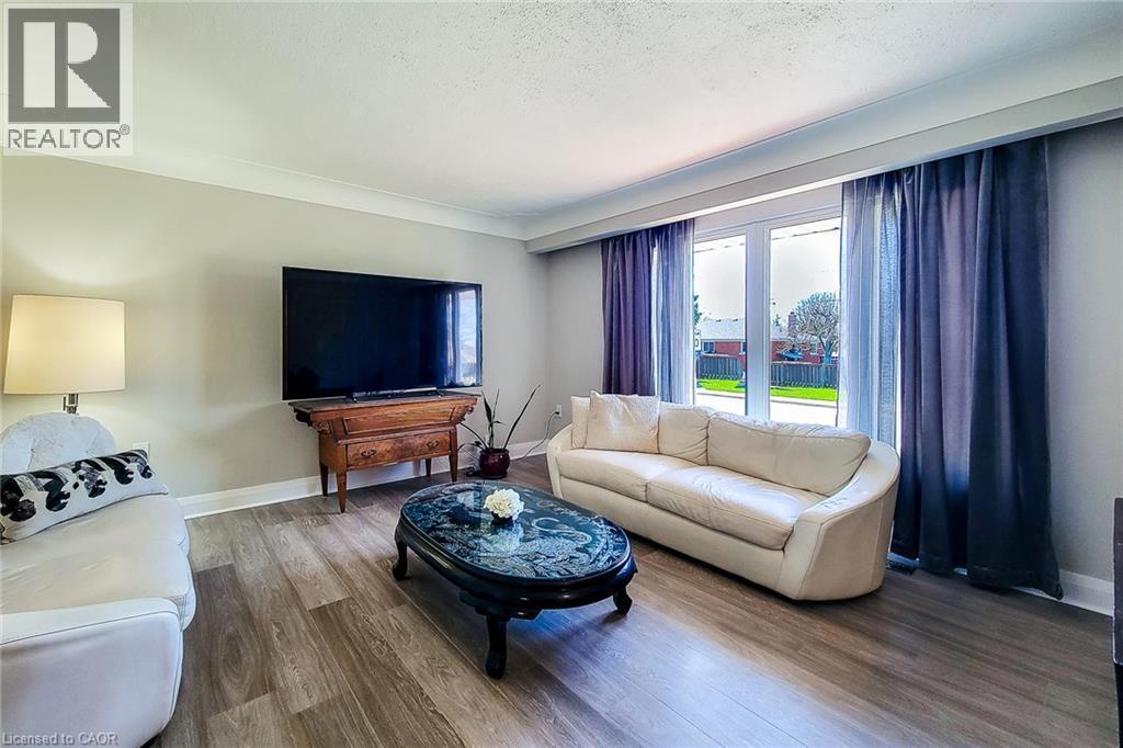 Bright living area featuring wood-finish flooring, a large window with ample natural light, and crown molding - 103 East 45Th Street, Hamilton, ON - Indoor Photo Showing Living Room