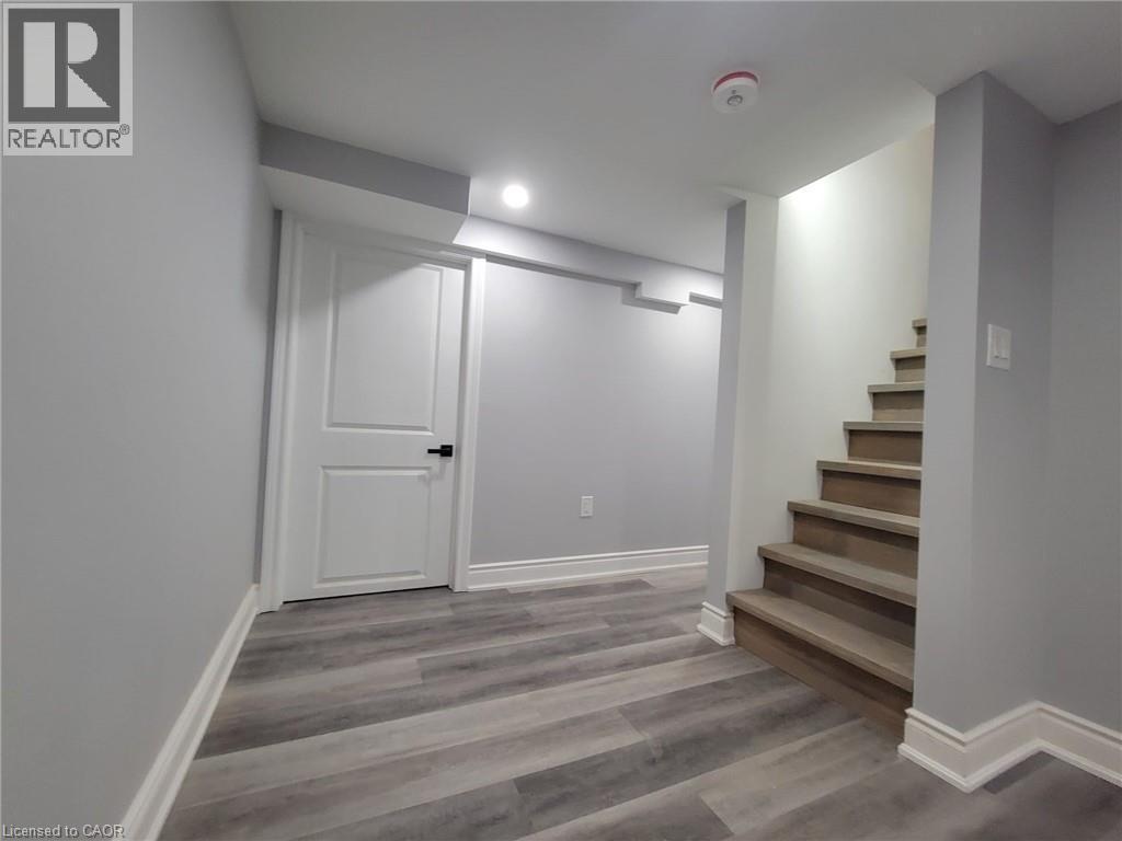 Finished lower level featuring wood-finish flooring, light grey wall paint, and white baseboards - 168 Garside Avenue N, Hamilton, ON - Indoor Photo Showing Other Room