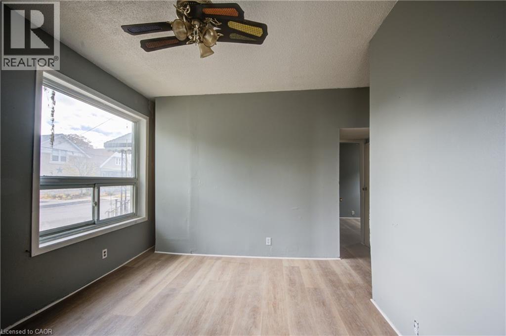 Unit 1A Living Room; Spacious room featuring wood-finish flooring, a large window with white trim, and a ceiling fan with integrated lighting - 1 Rathgar Street, London, ON - Indoor Photo Showing Other Room