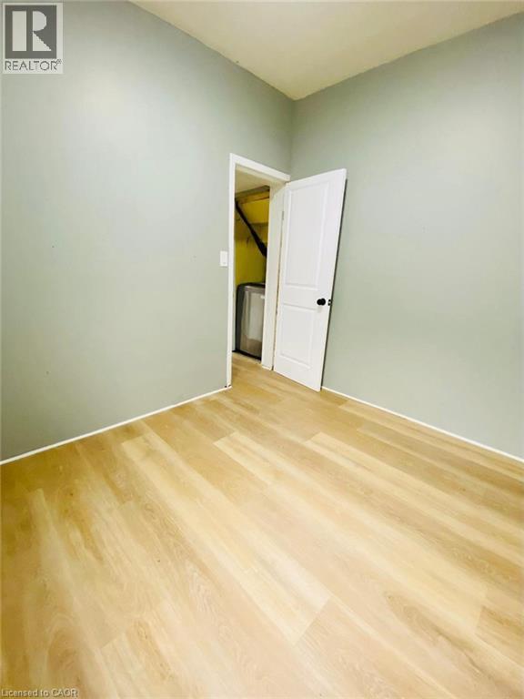 Unit 1A Bedroom; Room featuring light wood-finish flooring, light green painted walls, and white trim - 1 Rathgar Street, London, ON - Indoor Photo Showing Other Room