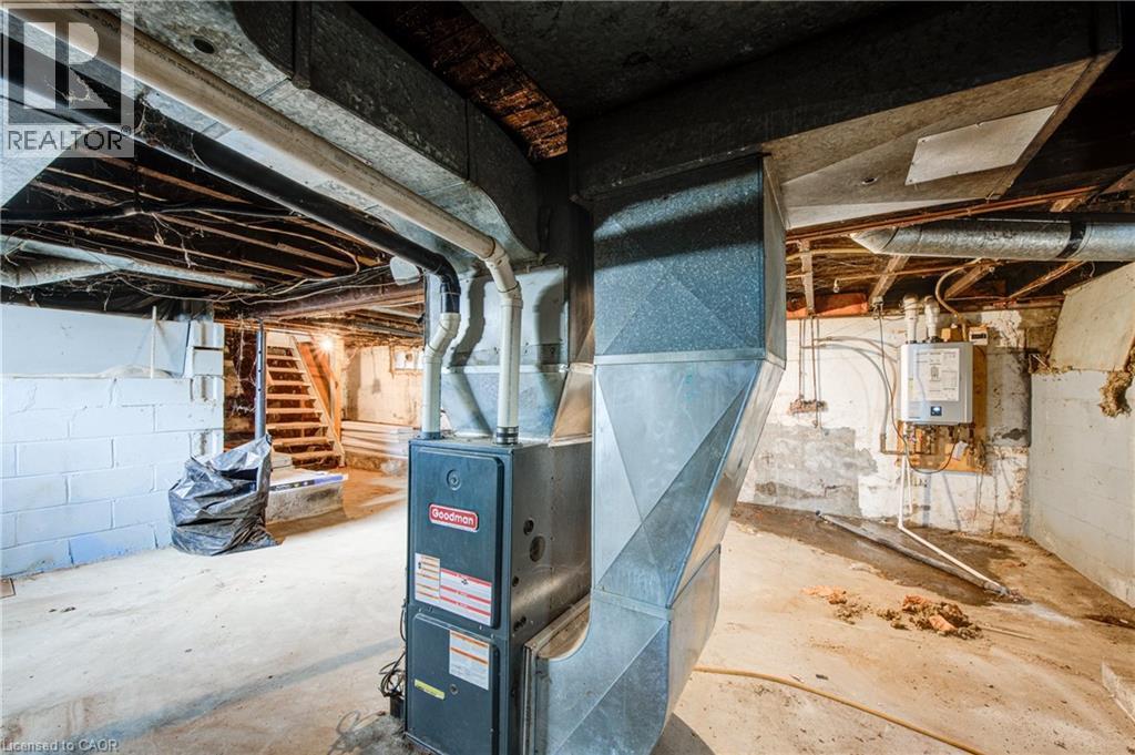 Basement space featuring a Goodman furnace unit, exposed ductwork, concrete flooring, and a visible water heater - 1 Rathgar Street, London, ON - Indoor Photo Showing Basement