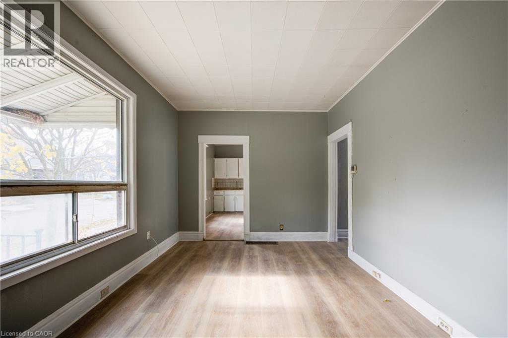 Spacious living room featuring wood-finish flooring, light gray wall paint, white trim, and a white paneled ceiling - 1 Rathgar Street, London, ON - Indoor Photo Showing Other Room