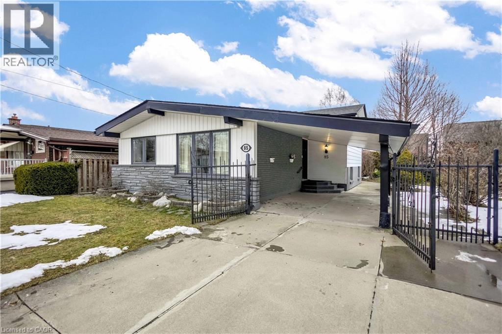 Mid-century modern exterior featuring a distinct roofline, white horizontal siding, and a stone-clad foundation - 85 Ranchdale Drive, Hamilton, ON - Outdoor