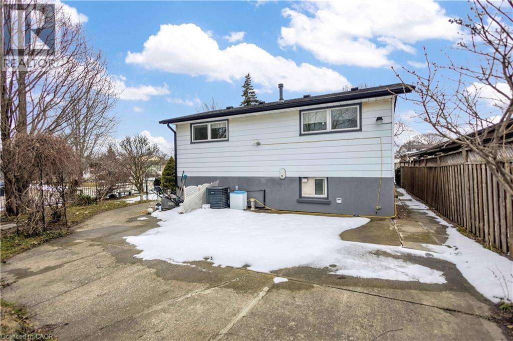 Split-level residence featuring light-colored siding, a dark-colored foundation, and a dark shingle roof - 85 Ranchdale Drive, Hamilton, ON - Outdoor