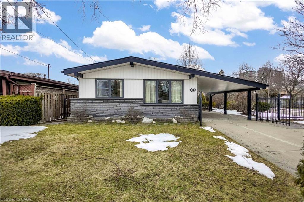 Exterior featuring a white facade with dark trim, stone veneer detailing, a covered carport, and a concrete driveway - 85 Ranchdale Drive, Hamilton, ON - Outdoor