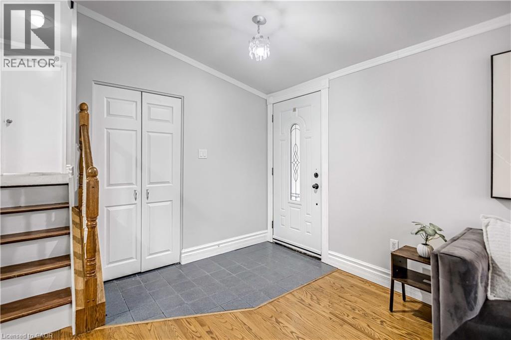 Entryway featuring a decorative glass paneled door, gray tile flooring, and a crystal chandelier - 85 Ranchdale Drive, Hamilton, ON