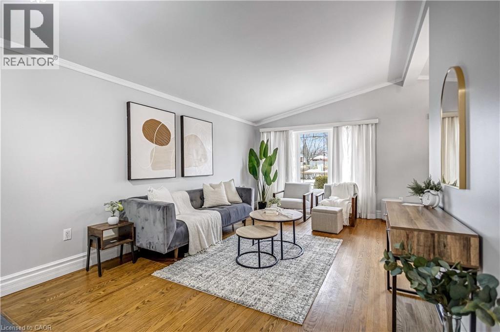 Spacious living area featuring wood-finish flooring, white crown molding, and a vaulted ceiling - 85 Ranchdale Drive, Hamilton, ON