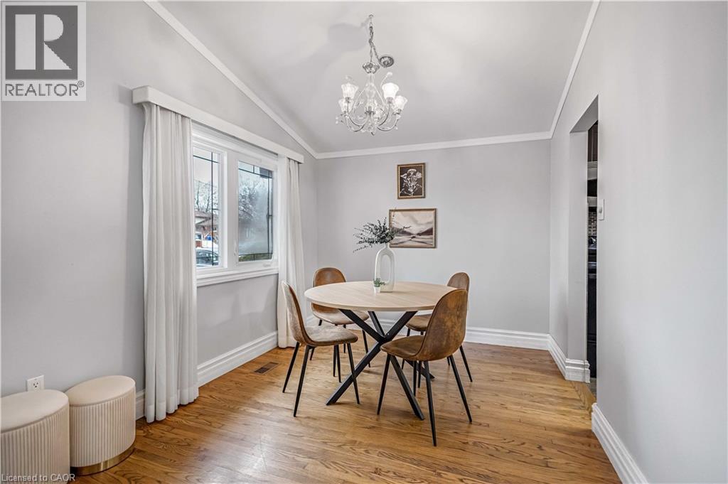 Dining area featuring hardwood flooring, a vaulted ceiling with crown molding, and a chandelier - 85 Ranchdale Drive, Hamilton, ON