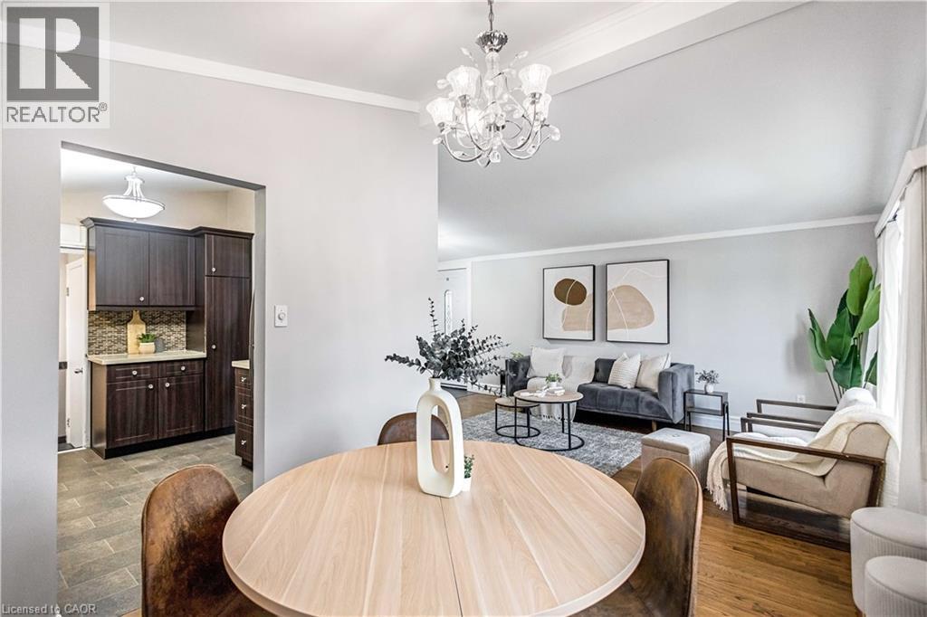 Dining area featuring a circular wood-finish table, a crystal chandelier, and crown molding - 85 Ranchdale Drive, Hamilton, ON