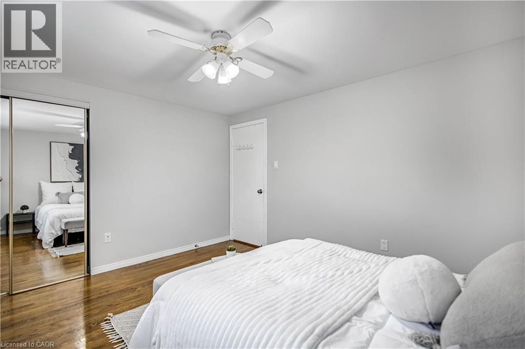 Bedroom featuring wood-finish flooring, light grey walls, and a white ceiling fan with integrated lighting - 85 Ranchdale Drive, Hamilton, ON