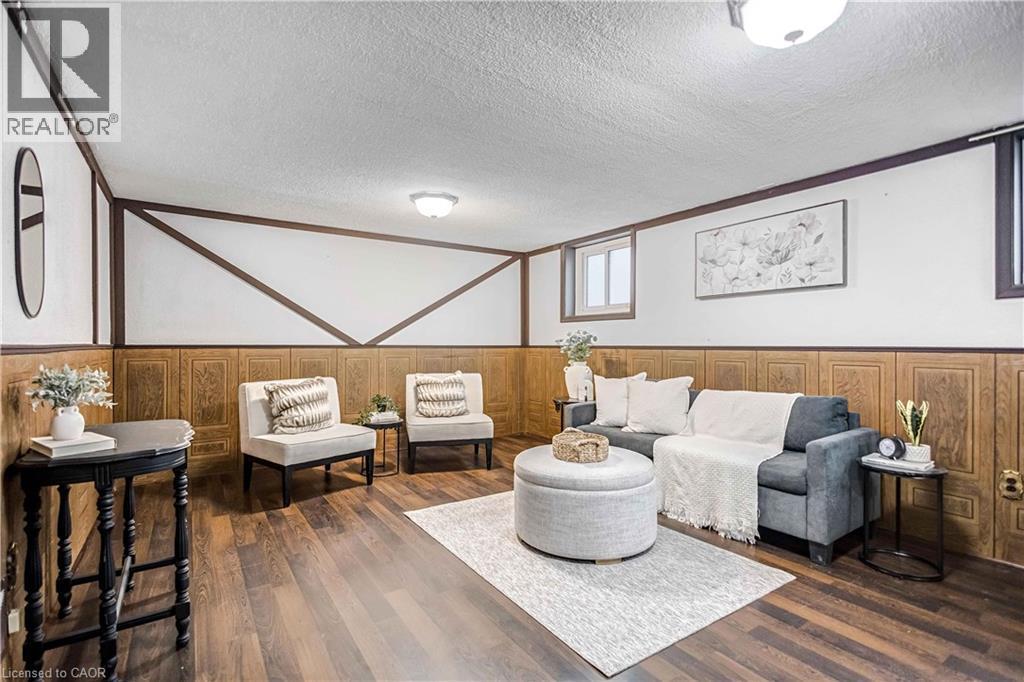 Finished lower level featuring wood-finish flooring, paneled walls, white ceilings, and recessed windows - 85 Ranchdale Drive, Hamilton, ON