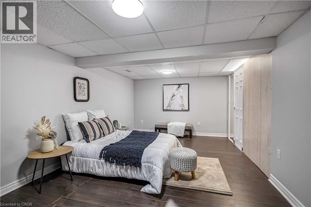 Spacious room featuring wood-finish flooring, light grey painted walls, and a dropped ceiling with integrated lighting - 85 Ranchdale Drive, Hamilton, ON