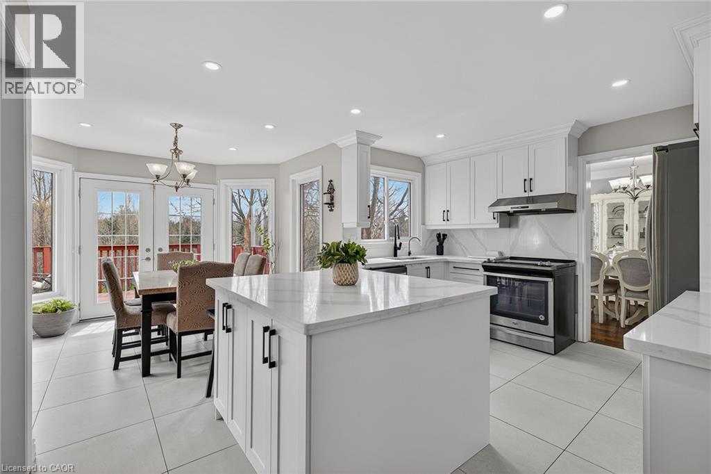Contemporary kitchen featuring white cabinetry, a central island with a solid surface countertop, stainless steel appliances, and a tiled backsplash - 79 Holbrook Crescent, Cambridge, ON - Indoor Photo Showing Kitchen With Upgraded Kitchen