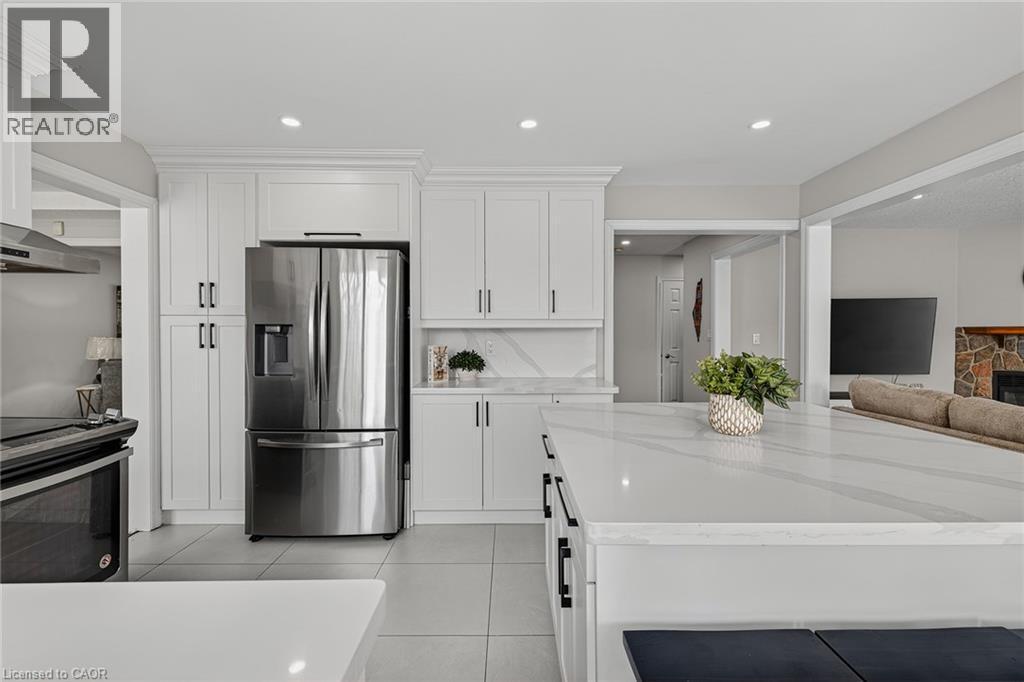 Modern kitchen featuring white shaker cabinetry, stainless steel appliances, a large center island with a light-toned countertop, and recessed lighting - 79 Holbrook Crescent, Cambridge, ON - Indoor Photo Showing Kitchen