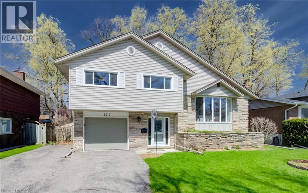 Split-level residence featuring a stone and siding exterior, an integrated garage, a bay window, and a manicured front lawn - 172 Rennie Drive, Kitchener, ON - Outdoor