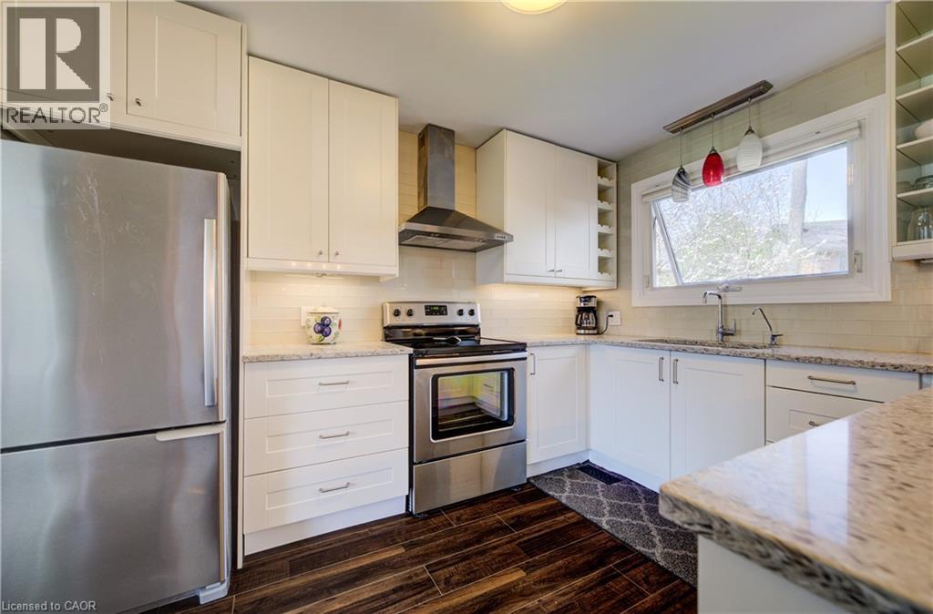 Kitchen featuring white cabinetry, stainless steel appliances, granite countertops, wood-finish flooring, and a subway tile backsplash - 172 Rennie Drive, Kitchener, ON - Indoor Photo Showing Kitchen With Upgraded Kitchen